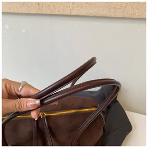 Detalle de asa de bolso marrón con costuras finas y textura elegante para moda de mujer.