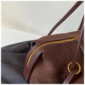 Vista detallada de la cremallera del bolso de hombro de ante marrón con diseño elegante.