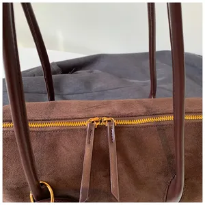Vista detallada del elegante bolso de hombro de ante marrón con cremallera y asa de mano.