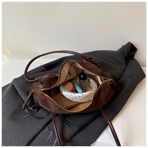 Detalle del bolso de hombro marrón minimalista de ante con textura suave y elegante.