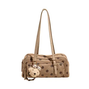 Gros plan détaillé du sac à épaule marron à pois élégant avec charm en peluche d'ours mignon.