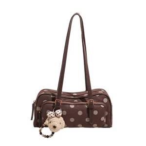 Vue détaillée du sac à épaule marron à pois avec longues bretelles et charm en peluche adorable.