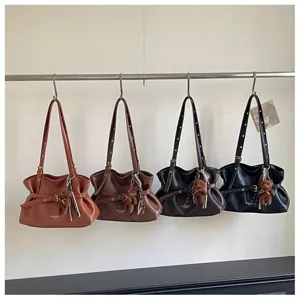 Detailed view of fashionable shoulder bags hanging on rack with cute bear plush pendants.