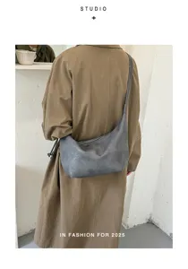 Detail close-up of a grey slouchy hobo shoulder bag styled with a brown trench coat.