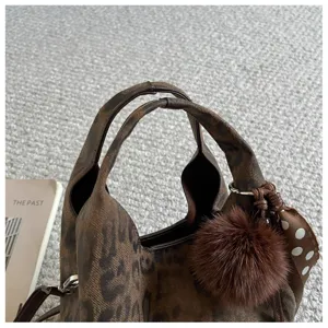 Detailansicht der stilvollen braunen Damenhandtasche mit Leopardenmuster und Plüsch-Anhänger.