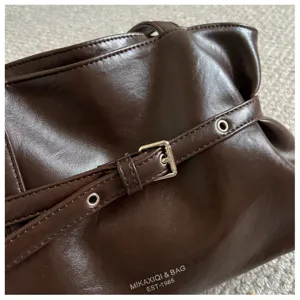 Brown leather shoulder tote bag detail featuring a chic metal buckle and minimalist style.