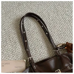 Detail view of dark brown PU leather tote bag with metal eyelets and cute bear charm.