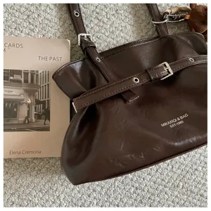 Dark brown PU leather shoulder tote bag with buckle belt and metal grommet detail.