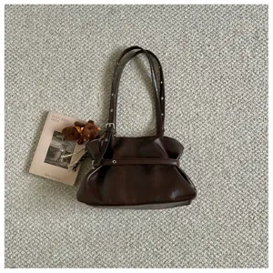 Detail shot of brown PU leather shoulder bag with slouchy design and chic buckled strap.