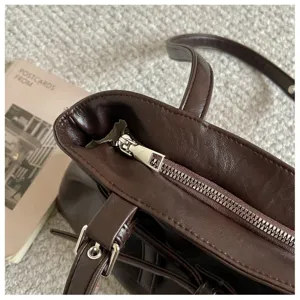 Dark brown PU leather tote bag zipper and buckle detail close-up view, stylish everyday shoulder bag.