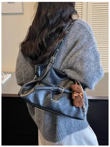 Black leather shoulder bag tote bag with buckle strap detail and cute bear charm pendant.