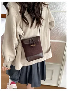 Detailed view of a brown suede and leather crossbody bag featuring a toggle button design.