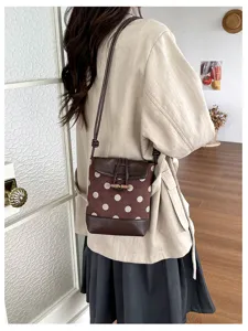 Detail view of stylish polka dot bucket bag with toggle closure and shoulder strap in daily use.