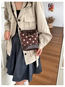 Detailed view of the stylish polka dot crossbody bucket bag with wooden toggle and strap.