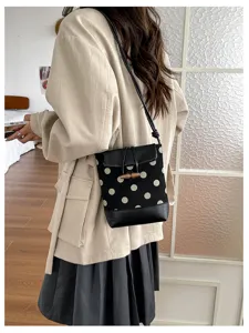 Detail view of the stylish polka dot bag featuring wooden toggle and chic shoulder strap.