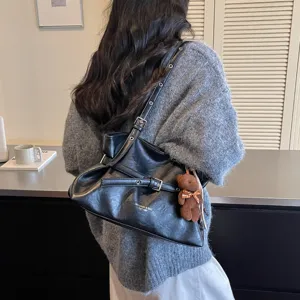 Fashion black leather shoulder bag with chic belt decor and cute bear pendant for daily commute.