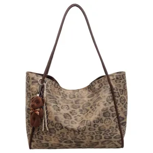 Leopard print tote bag detail showing brown shoulder straps and cute teddy bear pendant charm.