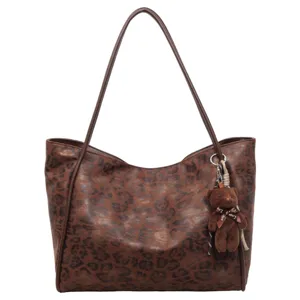 Close-up detail of the vintage leopard print tote bag with brown straps and a cute bear pendant.