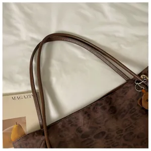 Close-up detail shot of brown leopard print tote bag featuring textured fabric and handles.