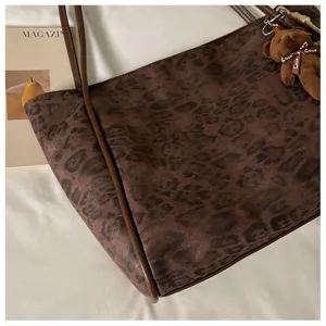 Vintage brown leopard print tote bag with leather handles and cute bear pendant detail.