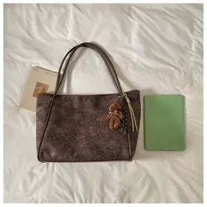 Detailed view of the vintage brown leopard print shoulder tote bag with cute bear charm.