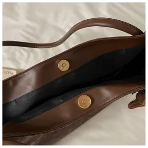 Retro brown leather shoulder bag detail, elegant underarm tote with metal magnetic snap.