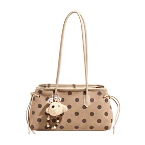 Detailed view of the beige polka dot shoulder tote bag with a cute cute bear plush charm.