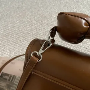 Close-up detail van de bruine handtas riem hardware en het strik handvat ontwerp.