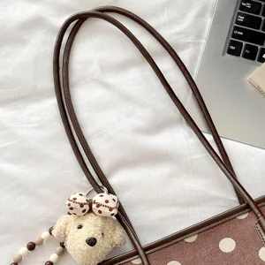 Brown polka dot shoulder bag strap detail featuring a cute puppy plush keychain pendant.