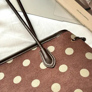 Close-up detail of brown polka dot shoulder tote bag featuring soft suede texture and leather piping.