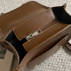 Bruine lederen tas detailweergave, ritsvak ontwerp, compact dagelijks mode-accessoire van dichtbij.