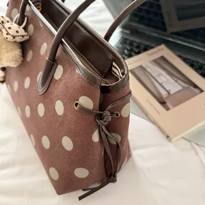 Brown polka dot tote bag detail view, suede texture with leather trim, side drawstring.