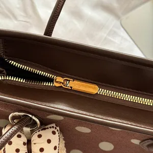 Brown polka dot tote bag detail view, stylish commuter shoulder bag with zipper closure.