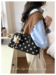 Detailed view of the vintage black polka dot shoulder bag with cute bear pendant in cozy room.