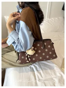 Detail view of a vintage polka dot shoulder bag with cute bear pendant for daily commute style.