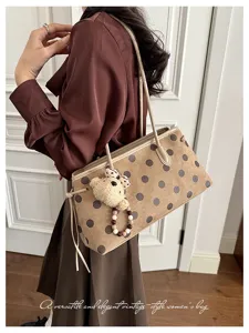Detailed view of brown polka dot vintage shoulder tote bag with cute bear charm and straps.