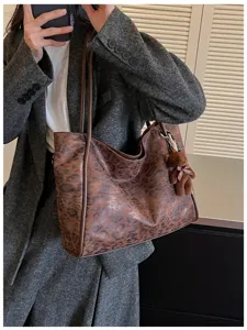 Leopard print tote bag detail, stylish shoulder bag with cute bear pendant in daily wear.