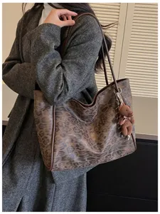 Detail shot of retro leopard print tote bag with cute bear keychain accessory, casual shoulder bag.