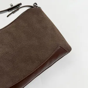 Brown textured leather shoulder bag detail closeup showcasing fine stitching and hardware.