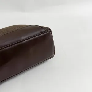 Brown leather handbag detail close up showing fine stitching texture and material quality.