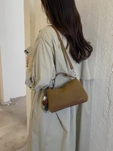 Brown autumn shoulder bag detail view, casual commuting crossbody handbag with charm accessory.