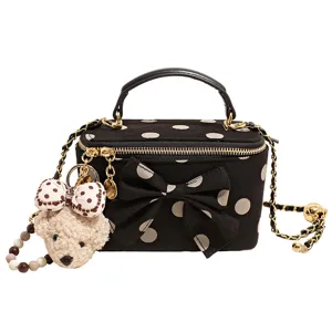 Detailed view of the black polka dot vanity box bag featuring a cute plush bear pendant.