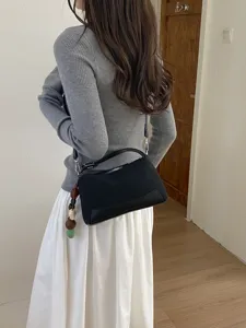 Stylish black shoulder bag for women with cute wooden bead charm, ideal for daily commute.