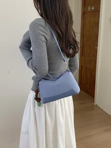 Detail shot of a stylish blue shoulder bag worn with casual outfit, showing its sleek design.