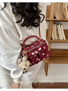 Detail shot of a vintage polka dot vanity bag with cute bow and plush bear pendant accessory.