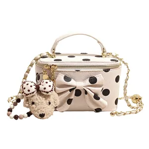 Stylish beige polka dot handbag with bow, cute plush puppy pendant, and chic chain strap.
