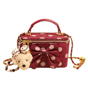 Red polka dot vanity bag with bow and teddy bear pendant, chic crossbody chain bag.