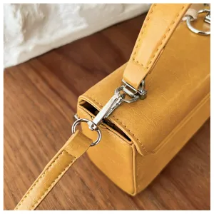 Yellow mini shoulder bag detail shot, PU leather crossbody purse with metal hardware and handle.