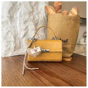 Stylish yellow women's shoulder crossbody bag with retro turn-lock and cute heart knitted pendant.