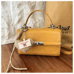 Yellow PU leather handbag with heart pendant, stylish detail view for women's daily commute.
